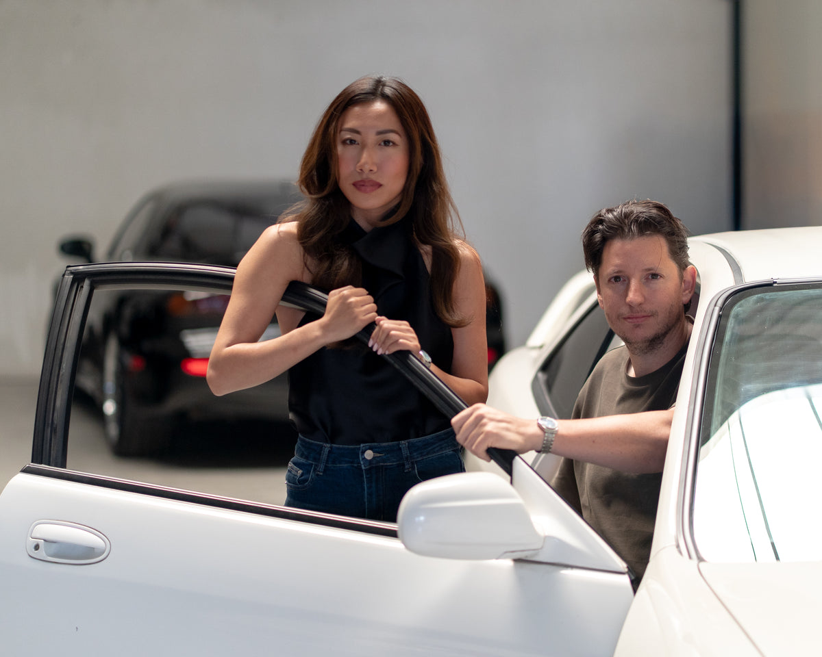 Mimi and Wouter beside a white Japanese sports car in the TougeSupply garage